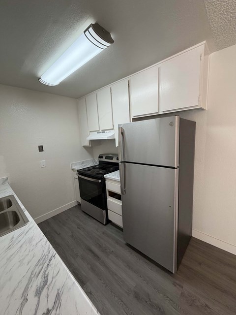 A kitchen with a refrigerator, oven, and sink.