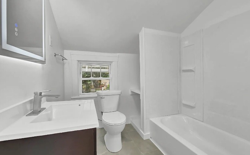 A white bathroom with a toilet, sink, and bathtub.