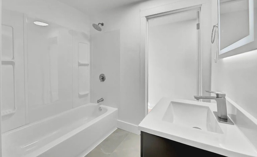 A white bathroom with a sink, bathtub, and shower.
