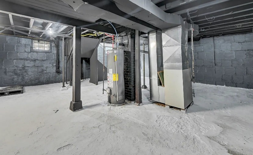A room with a concrete floor and walls, a metal beam ceiling, and a large industrial machine.