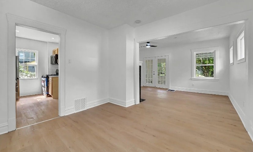 A room with wooden floors and white walls, with a door leading to another room.
