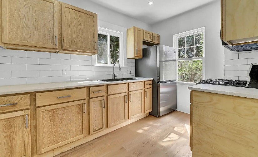 A kitchen with wooden cabinets and a stainless steel refrigerator.