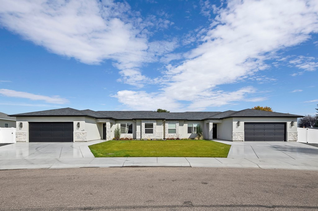 A large house with a grey roof and a green lawn in front.
