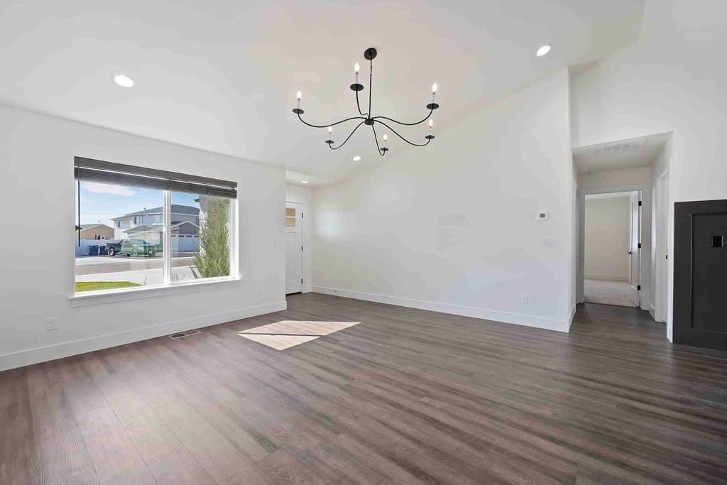 A room with a chandelier, a rug, and a window with a view of a street.