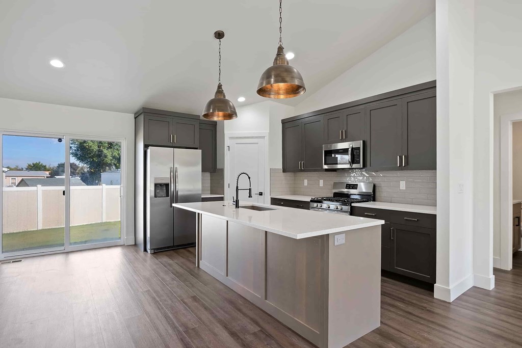 A modern kitchen with a white island and dark grey cabinets.