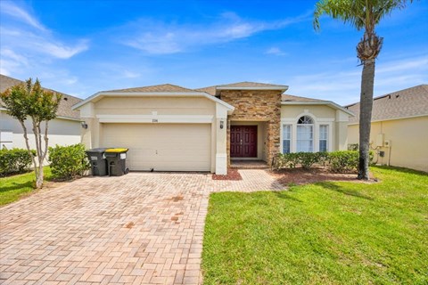 A house with a driveway and a palm tree in front.