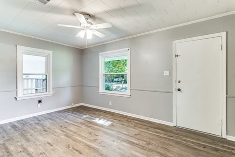 A room with a ceiling fan and two windows.