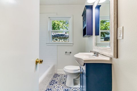 A bathroom with a toilet, sink, and a window.