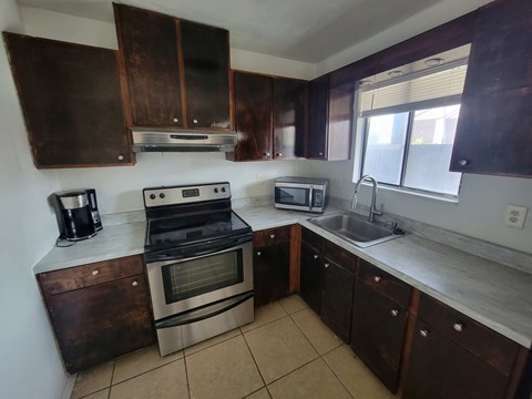 A kitchen with brown cabinets and a stove top oven.
