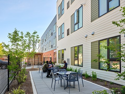 A group of people are sitting at a table outside of a building.