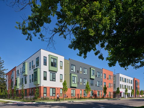 A row of modern townhouses with green trees in the foreground.