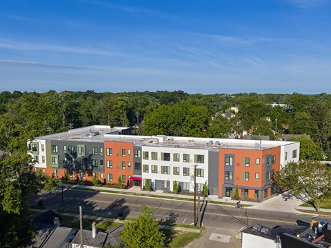 A multi-story building with a red and white facade is surrounded by trees.