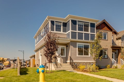 A two-story house with a grey exterior and a yellow fire hydrant in front.