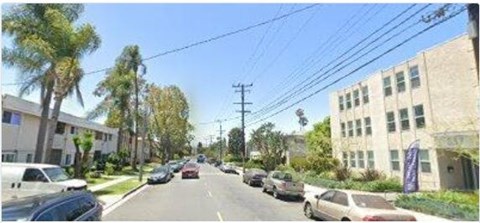 A street with cars parked on the side and buildings on both sides.