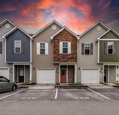 A row of houses with garages and a car parked in front.