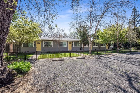 A house with a gravel driveway and trees in the background.