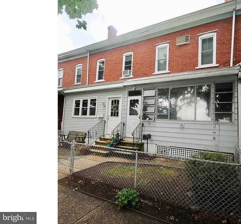 A red brick building with a white fence in front.