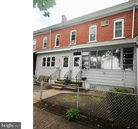A red brick building with a white fence in front.