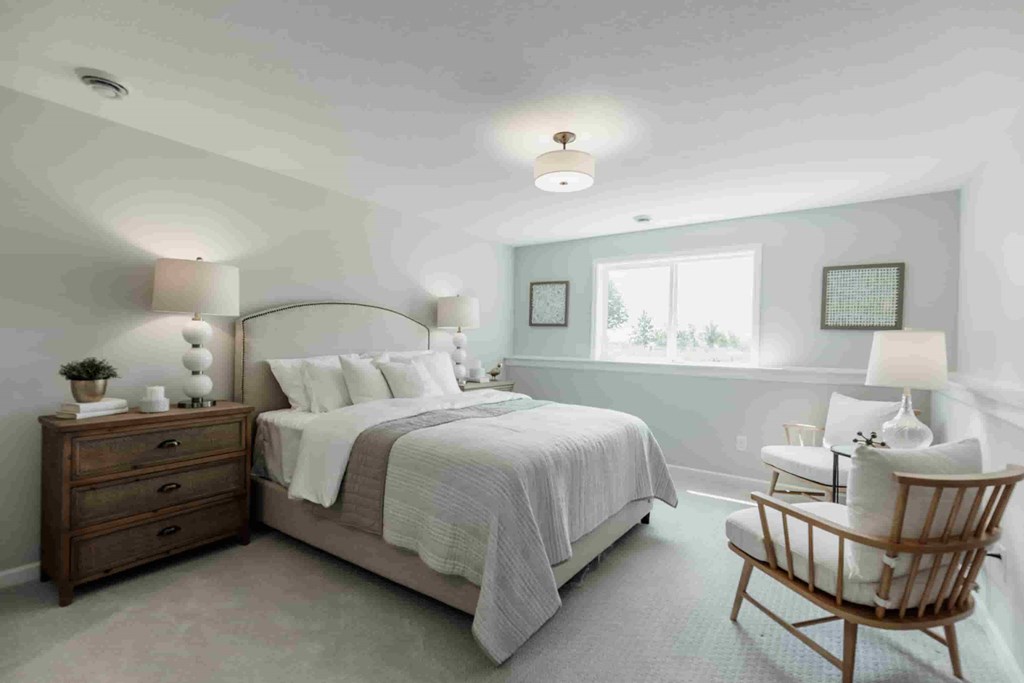 A bedroom with a bed, nightstand, and chair.