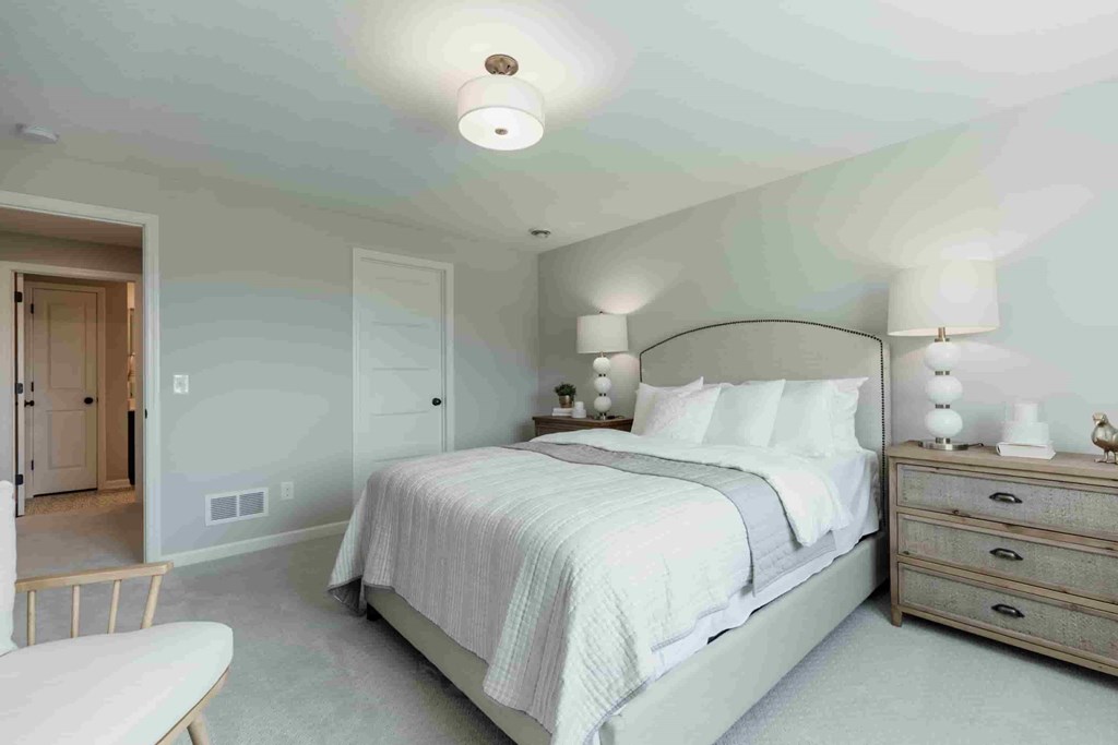 A bedroom with a bed, nightstand, and chair.