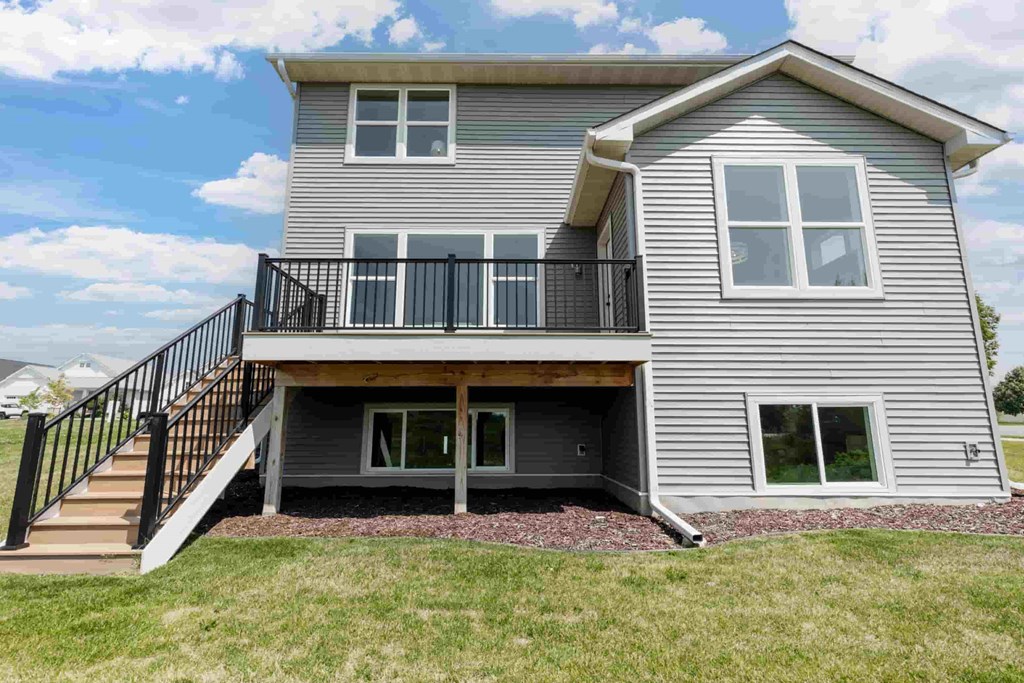 A grey house with a black railing on the balcony.