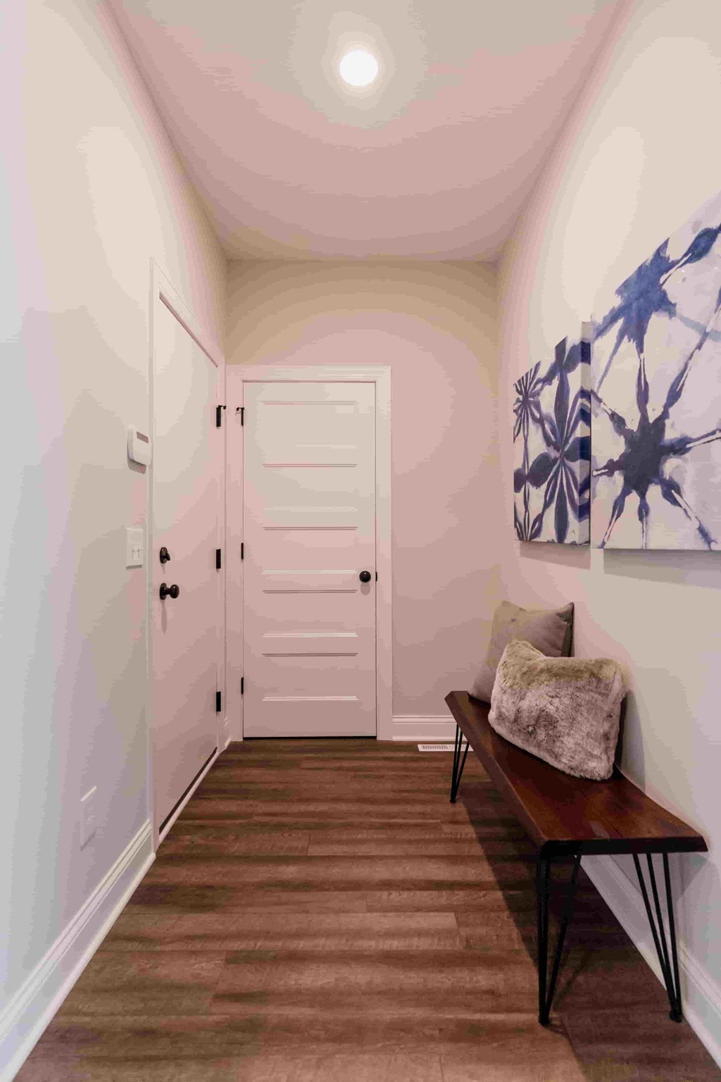 A hallway with a bench and a door.