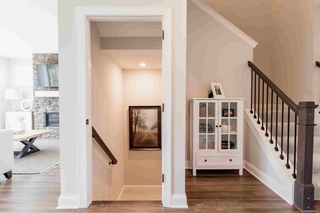 A hallway with a staircase and a cabinet with glass doors.