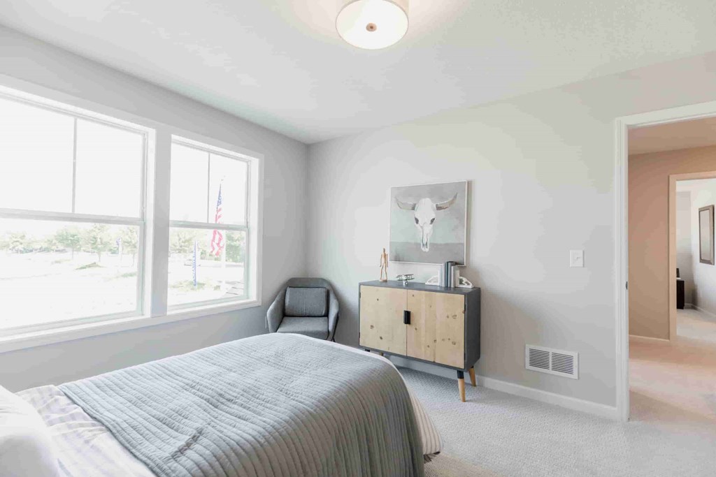 A bedroom with a bed, nightstand, and chair.