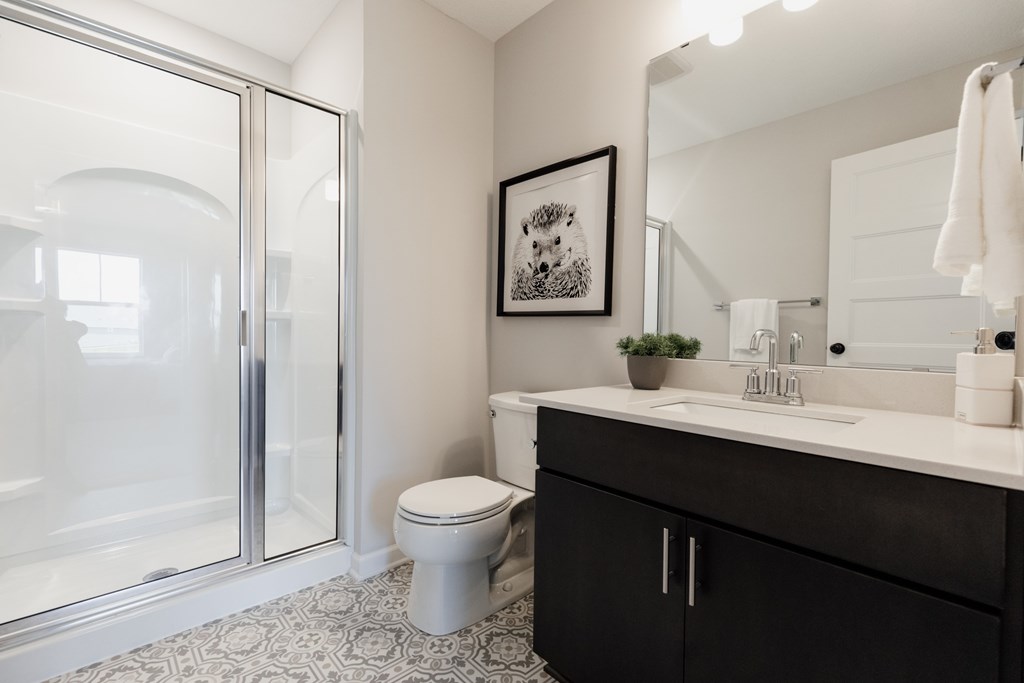 A bathroom with a toilet, sink, and mirror.