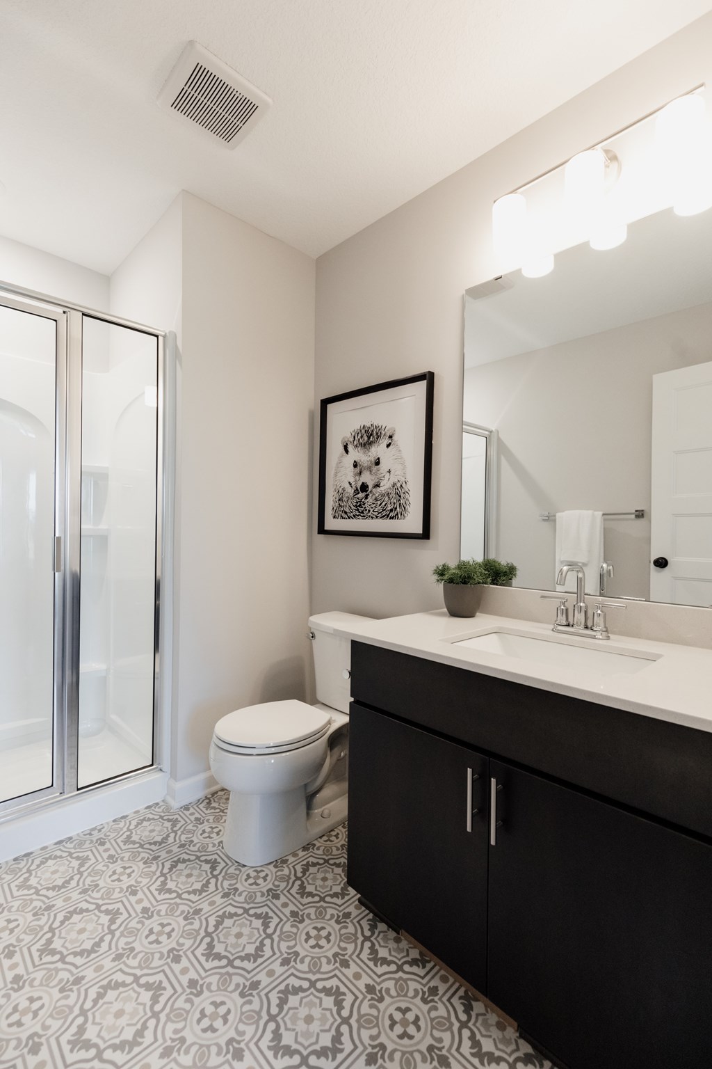 A bathroom with a toilet, sink, and a framed picture on the wall.
