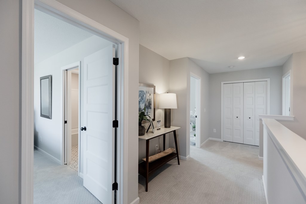 A well-lit, spacious room with a white door and a table with a lamp.