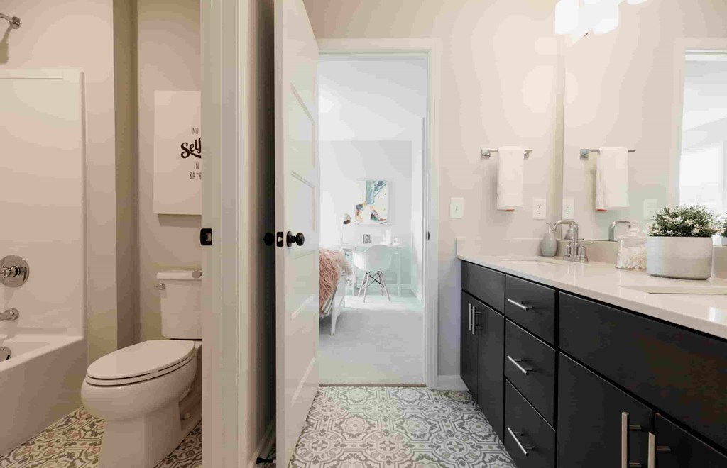 A bathroom with a toilet, sink, and a mirror.