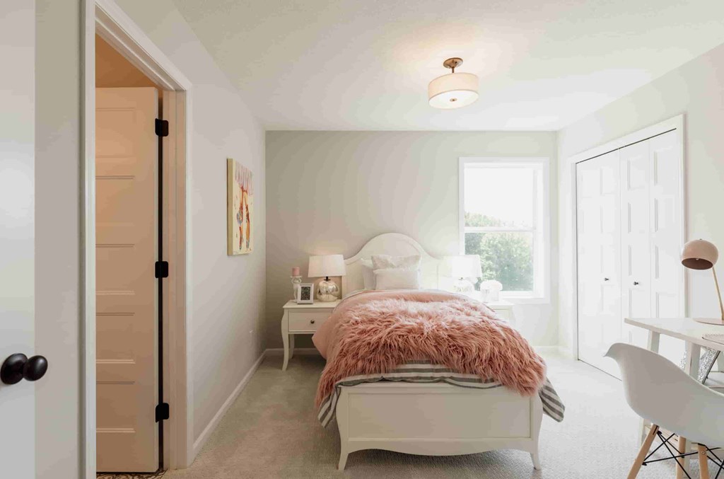 A bedroom with a bed, chair, and lamp.