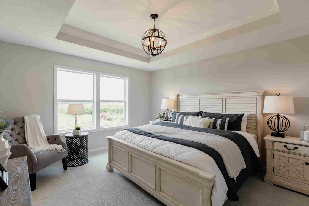 A bedroom with a large bed, a chair, and a window.