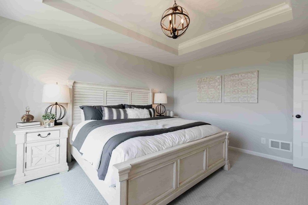 A bedroom with a large bed and a chandelier.