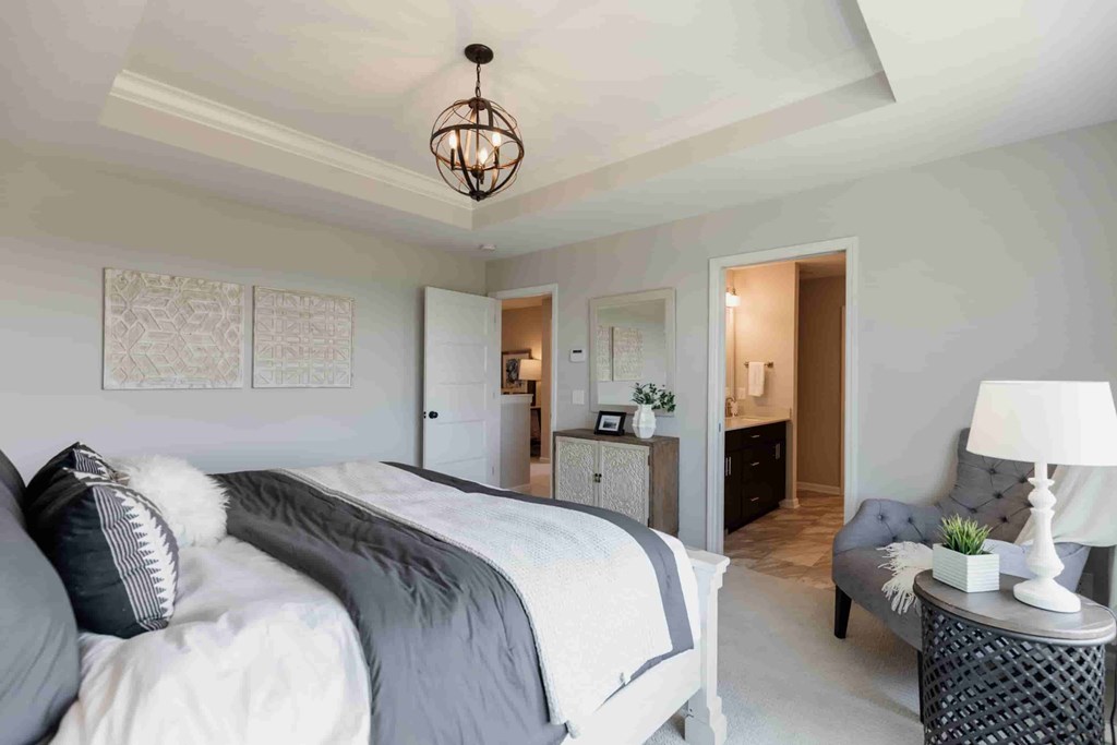 A bedroom with a large bed and a chair.