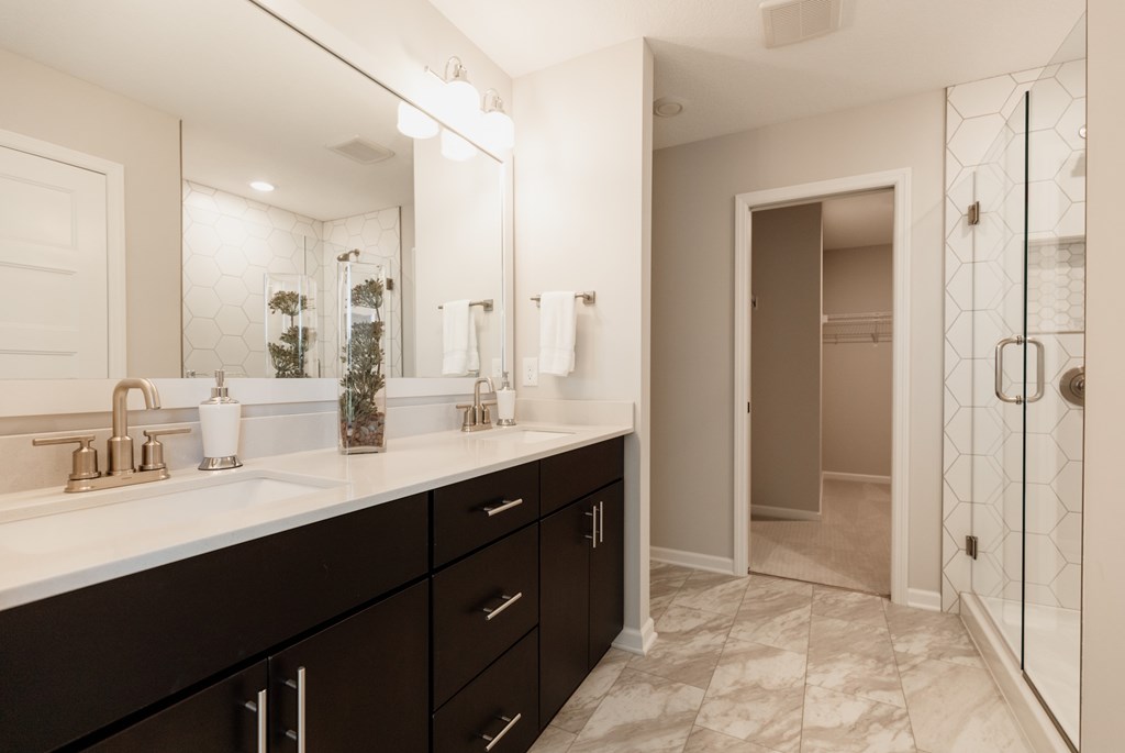 A bathroom with a sink, mirror, and a shower.