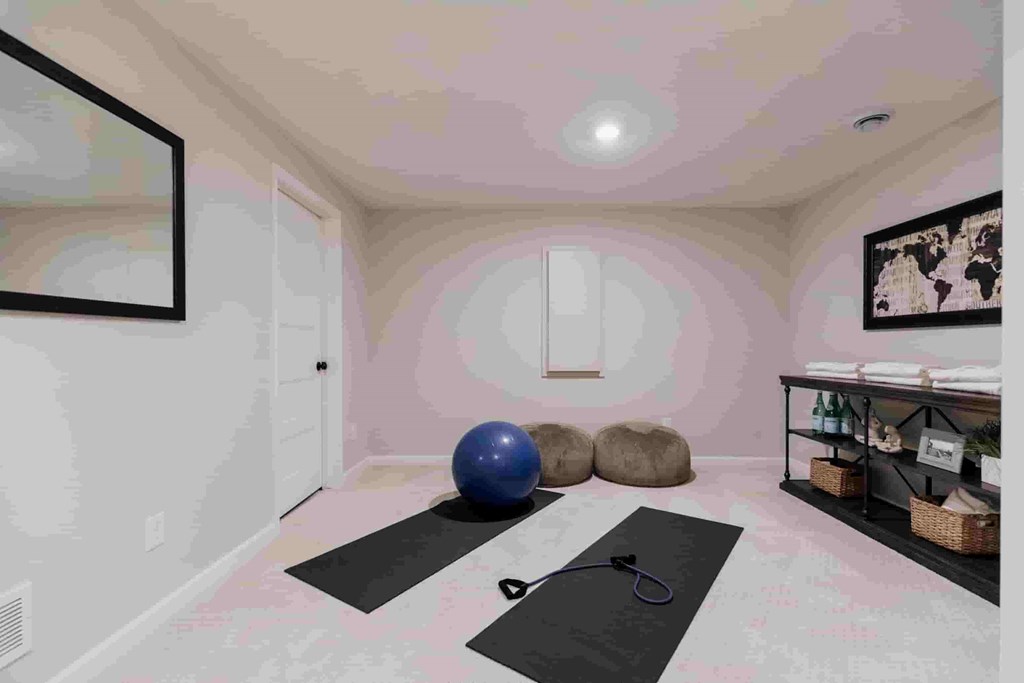 A room with a yoga mat, exercise ball, and a pair of scissors on the floor.