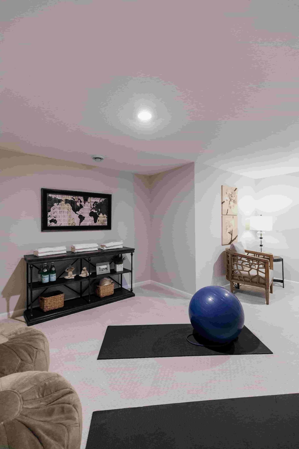 A room with a blue exercise ball on a black mat.