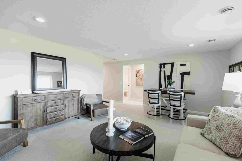 A living room with a grey sofa, a wooden coffee table, and a wooden cabinet with a mirror above it.