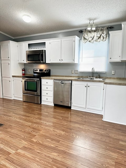 A kitchen with white cabinets and wooden floors.
