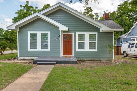 A small house with a brown door and a grey roof.