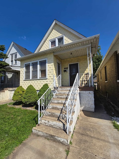 A yellow house with a white door and windows.