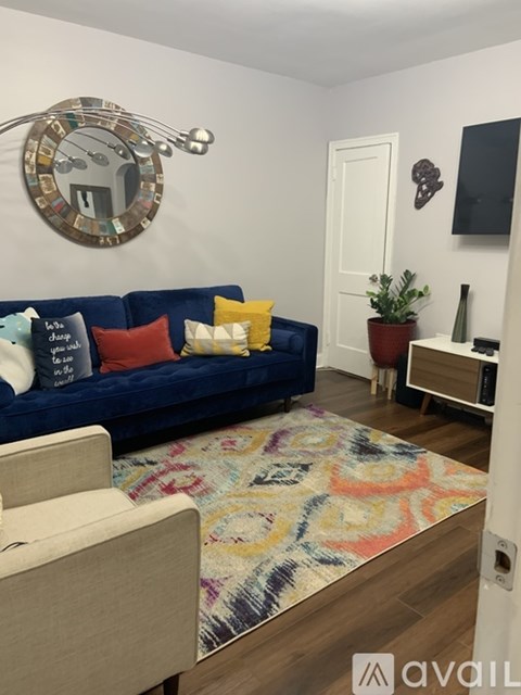 A living room with a blue couch and a round mirror on the wall.