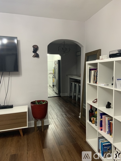 A living room with a television, a bookshelf, and a plant.
