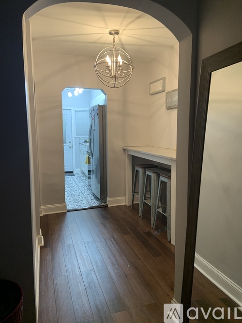 A hallway with a light hanging from the ceiling and a doorway leading to another room.