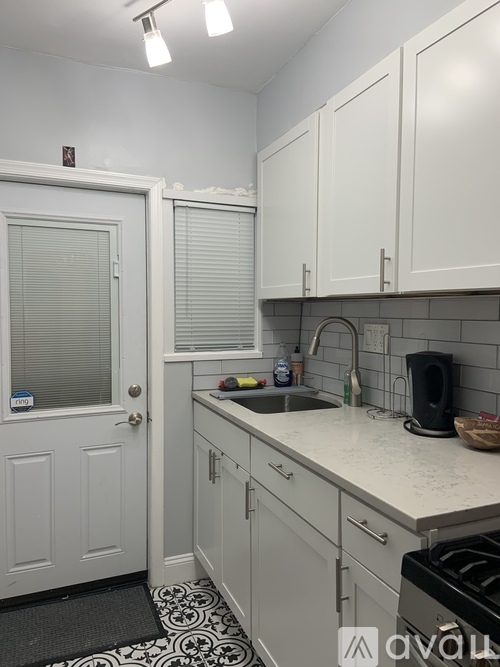 A kitchen with white cabinets and a black and white floor mat.