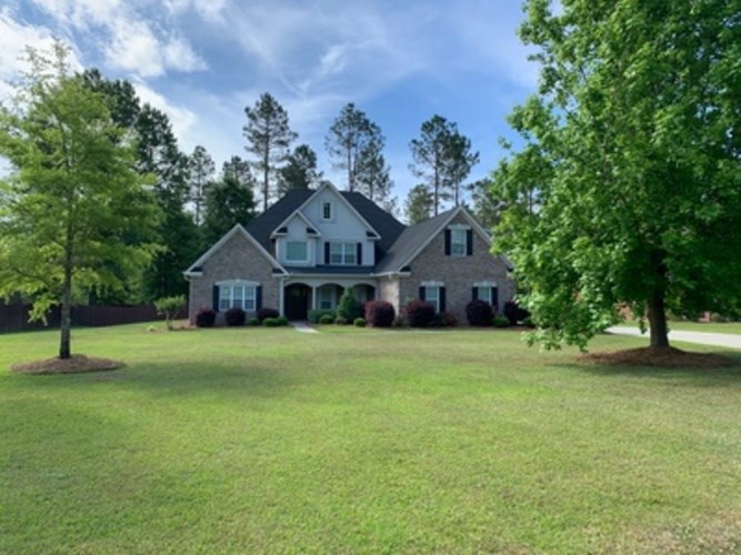 A house with a large lawn and trees in front.