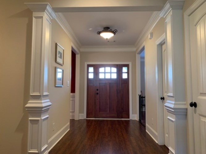 A hallway with a wooden floor and white walls.