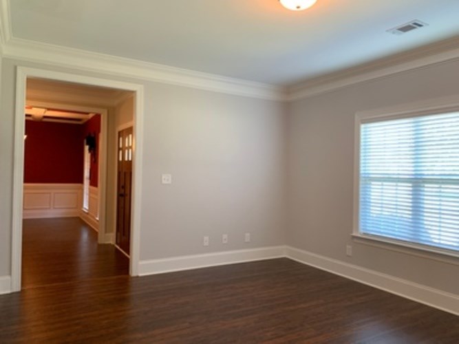 A room with a wooden floor and a window with blinds.